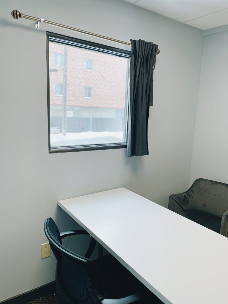 Private office with multiple chairs at a desk, and large window.