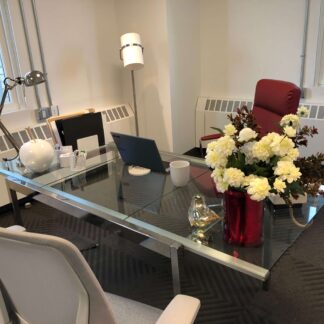 Private office with flowers and glass desk, with other amenities visible.