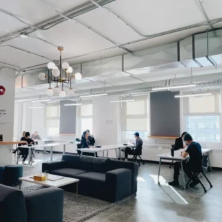Large coworking area with multiple amounts of people working in the background.