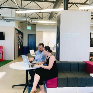 Two coworking members talking at a desk with laptop visible.